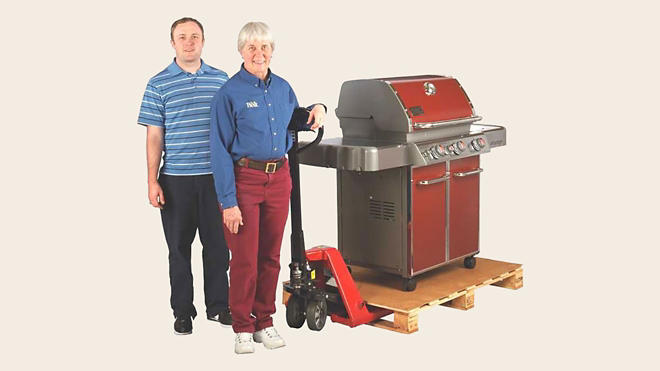 Two people standing next to a grill 