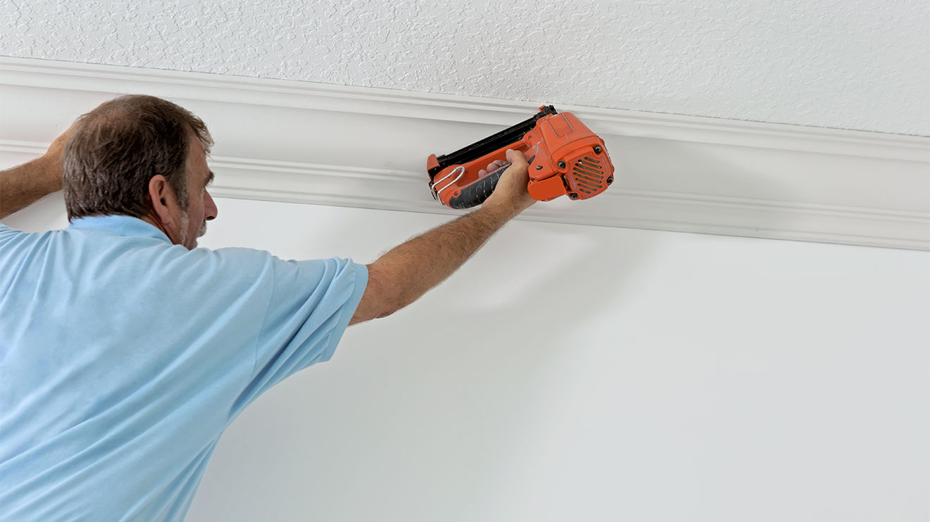 A man installing crown moulding