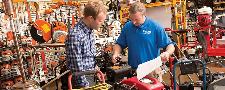 Two men inspecting a rental power equipment in a rental center 