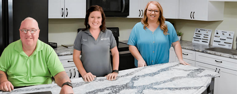 Three Gillman Home Center employees standing in front of a marbled island.