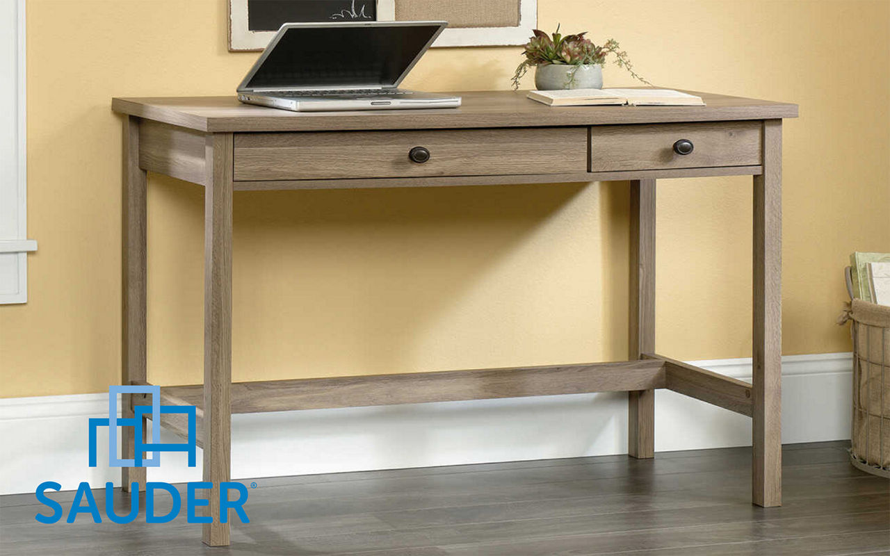 Sauder desk with an open laptop on top of it near a plant