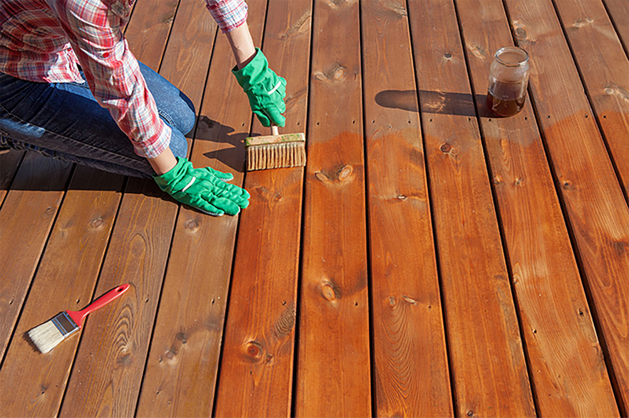 Person on their deck washing it to get ready for the waterproof transparent stain