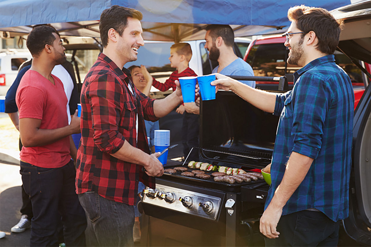 Guys tailgaiting and clinking their blue cups