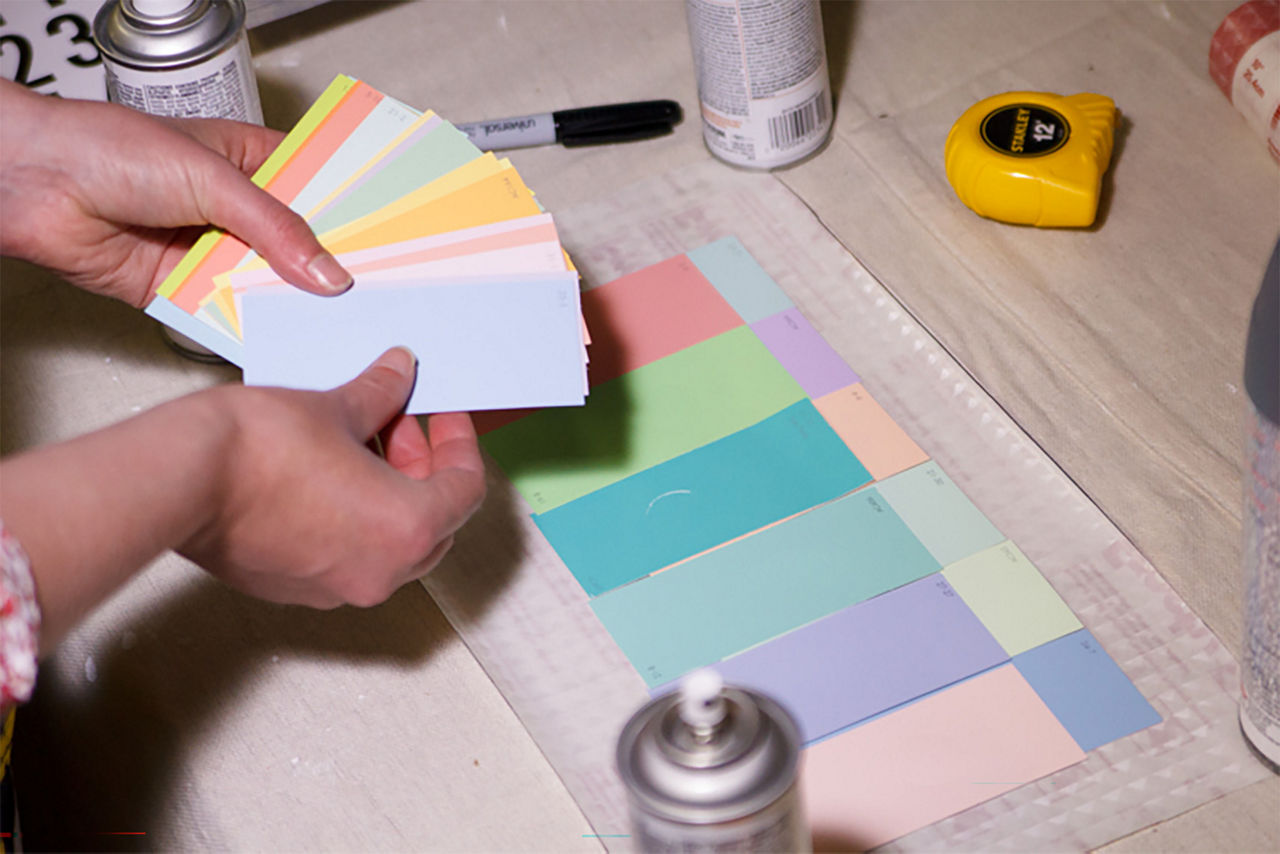 Person holding the color swatches to line them up inside the window pane quadrant