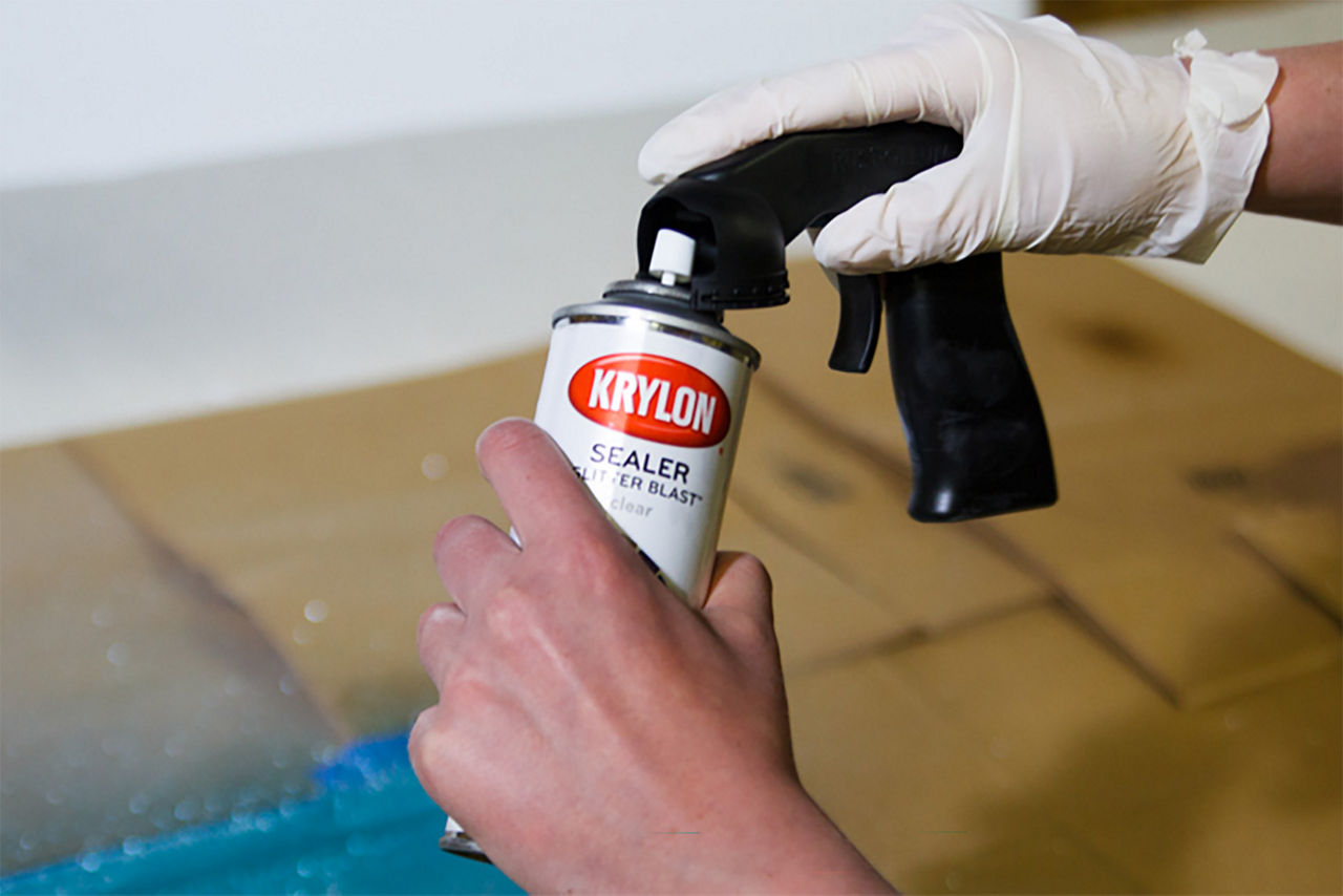 Close up of someone prepping the can of krylon sealer to spray over the glitter on the window pane