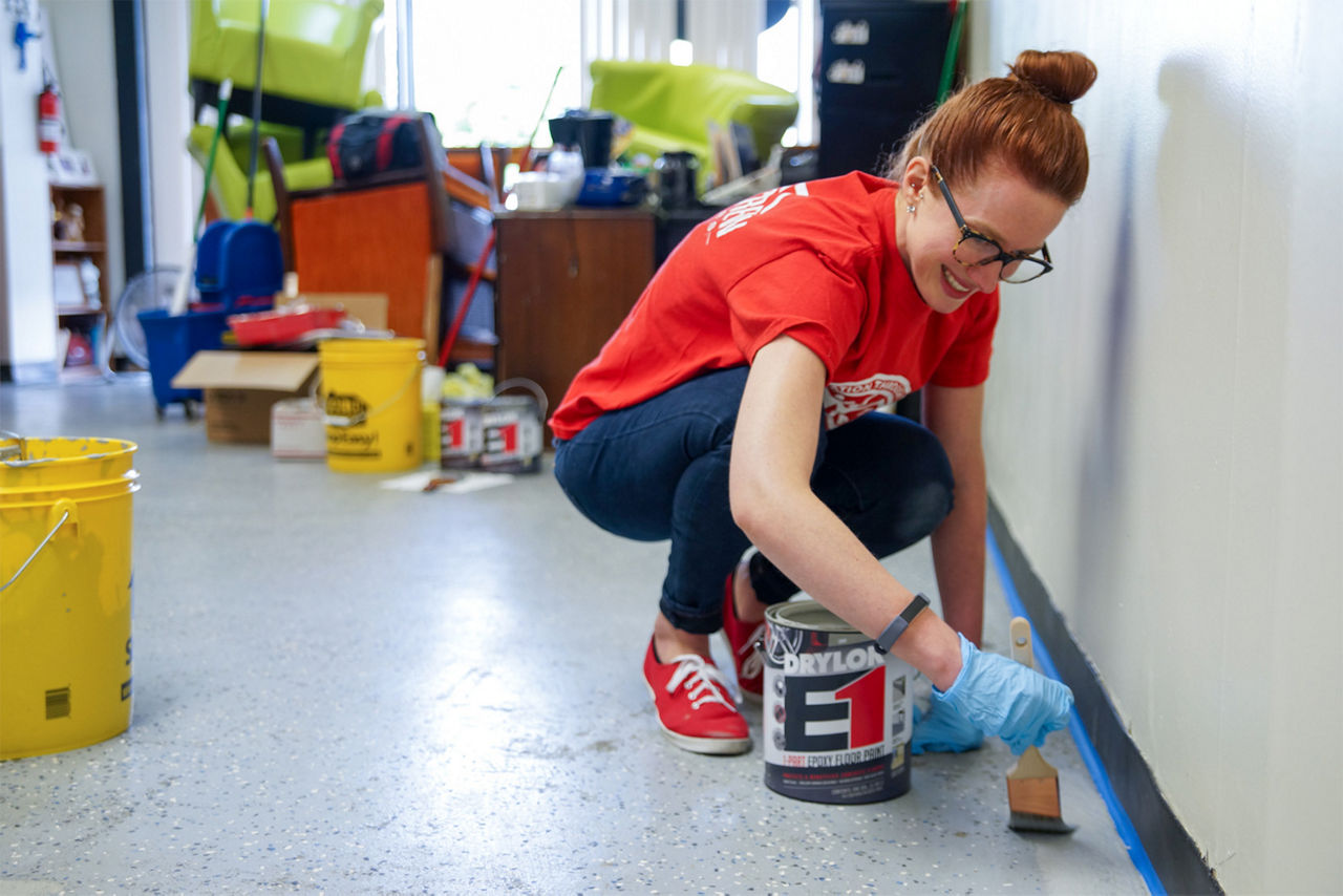 A girl painting the edges of the floor with the epoxy floor paint