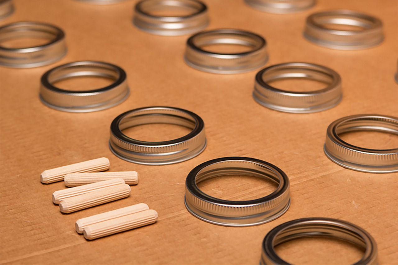 Laid out mason jar rings and dowels on a flat surface to get painted