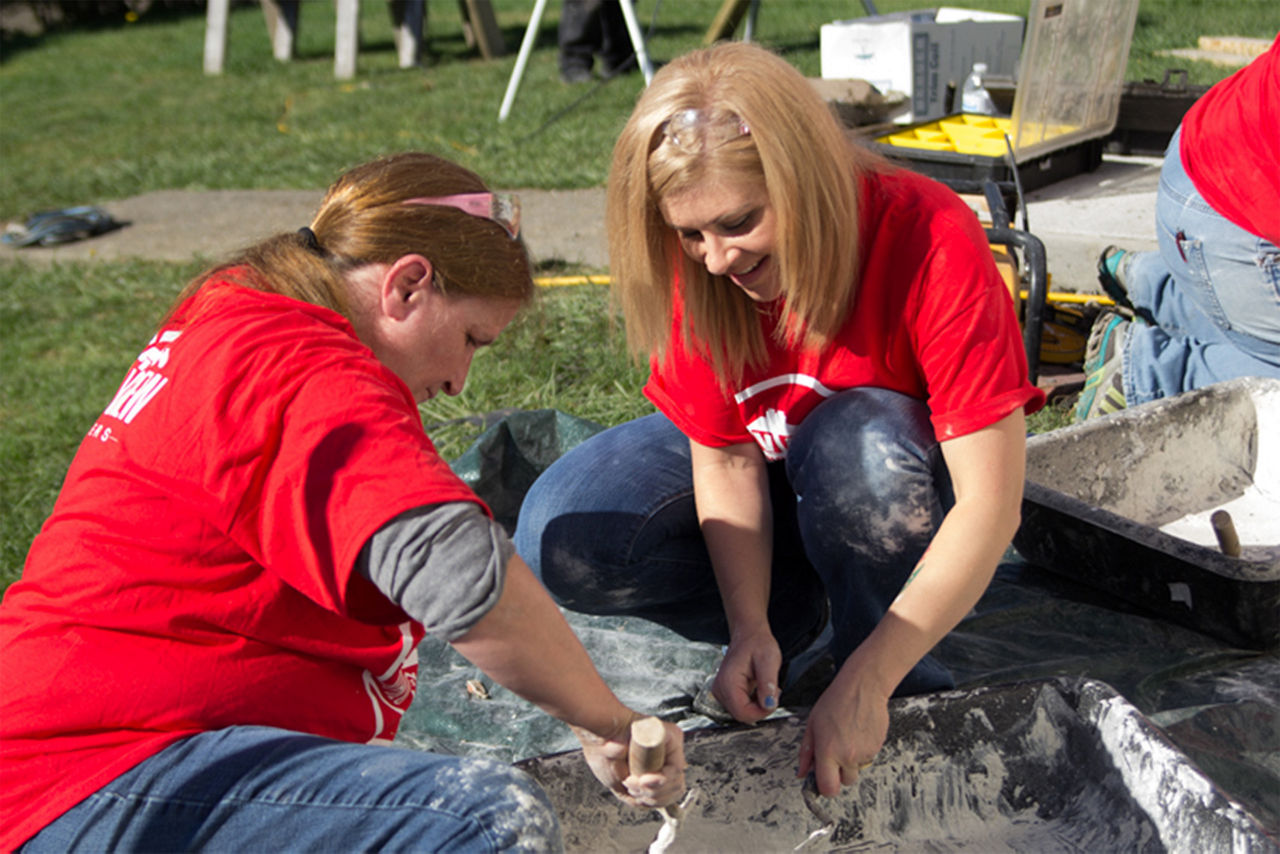 Two women scraping wet concrete