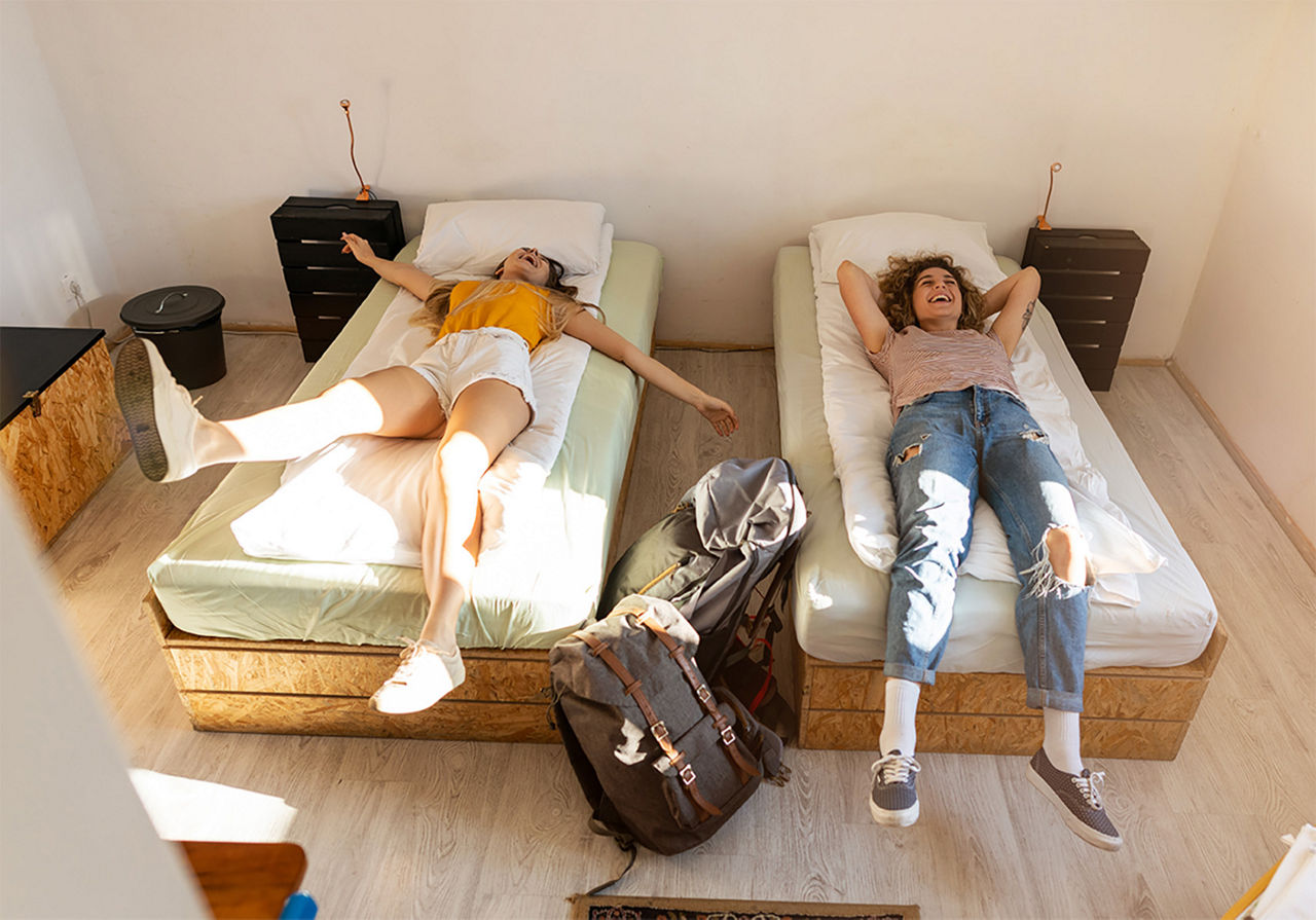 Two girlsd laying on their new dorm rooms beds with excitement