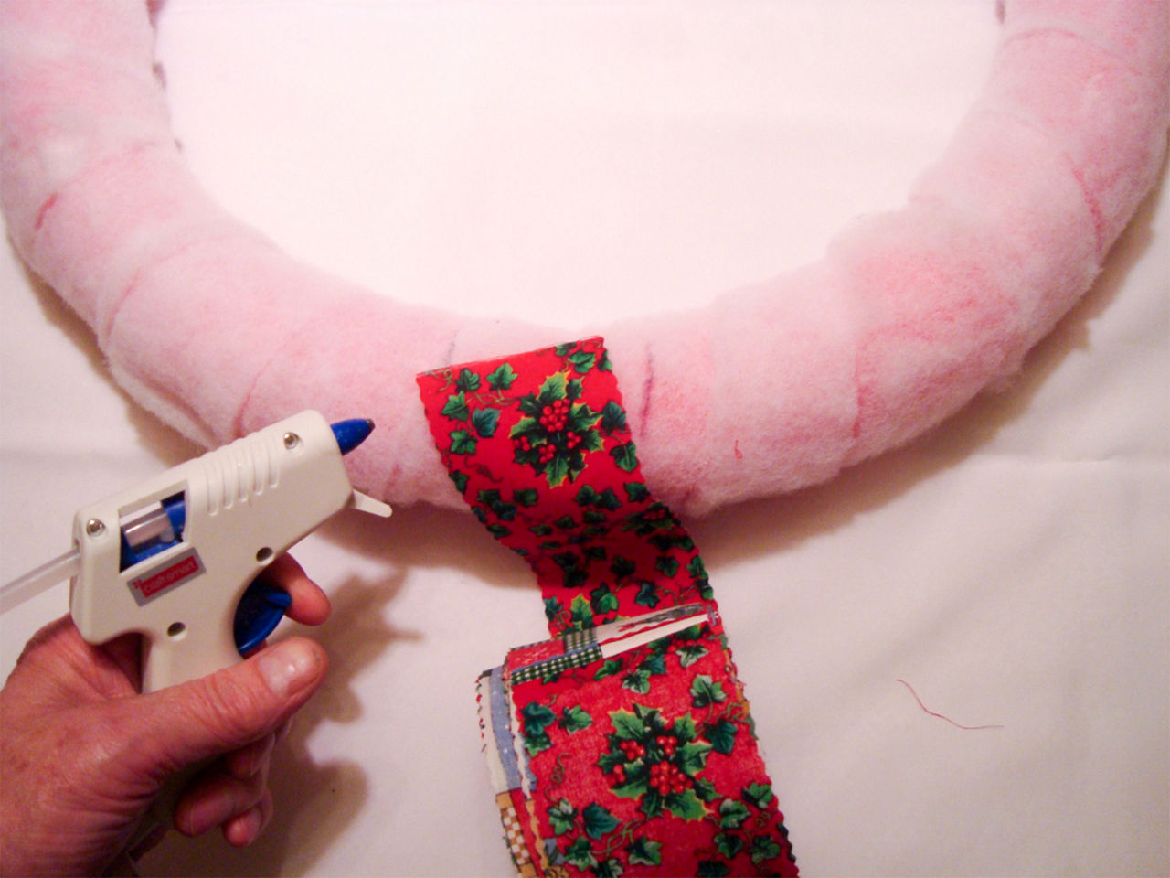 Putting the fabric over the batting on the pool noodle and getting your hot glue gun