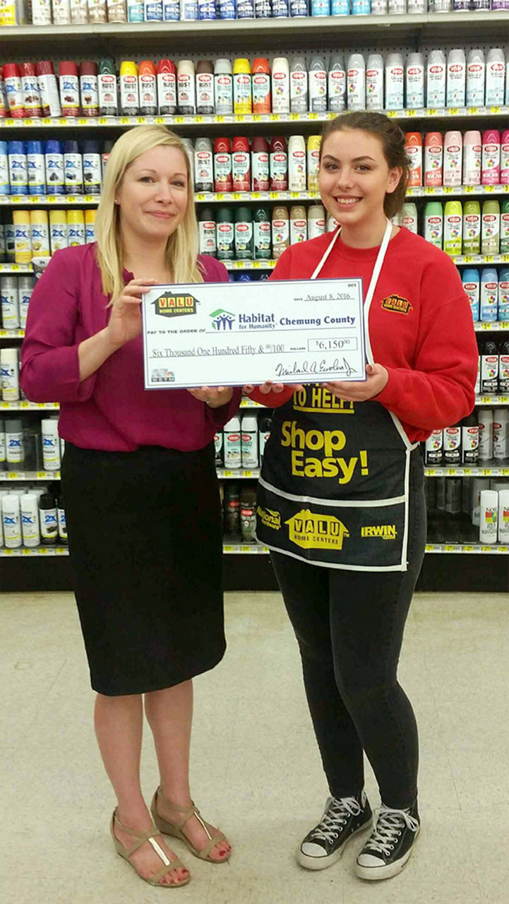 Two women with a check for selling the most raffle tickets