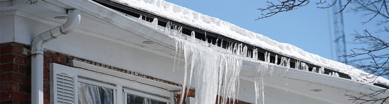Icicles pulling down on a white gutter