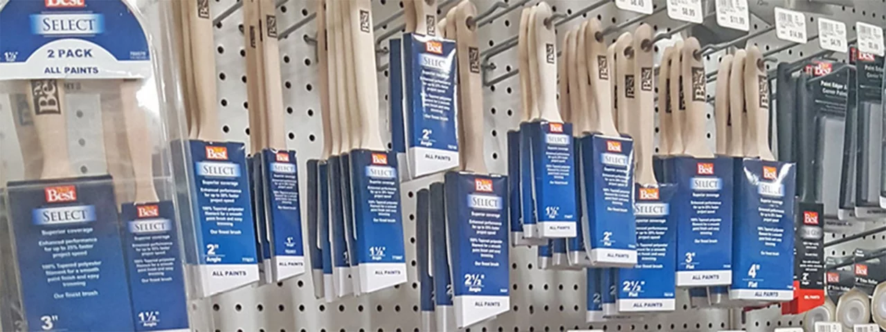 a store isle lined with peg boards and hooks holding rows of new paintbrushes in ablue packaging
