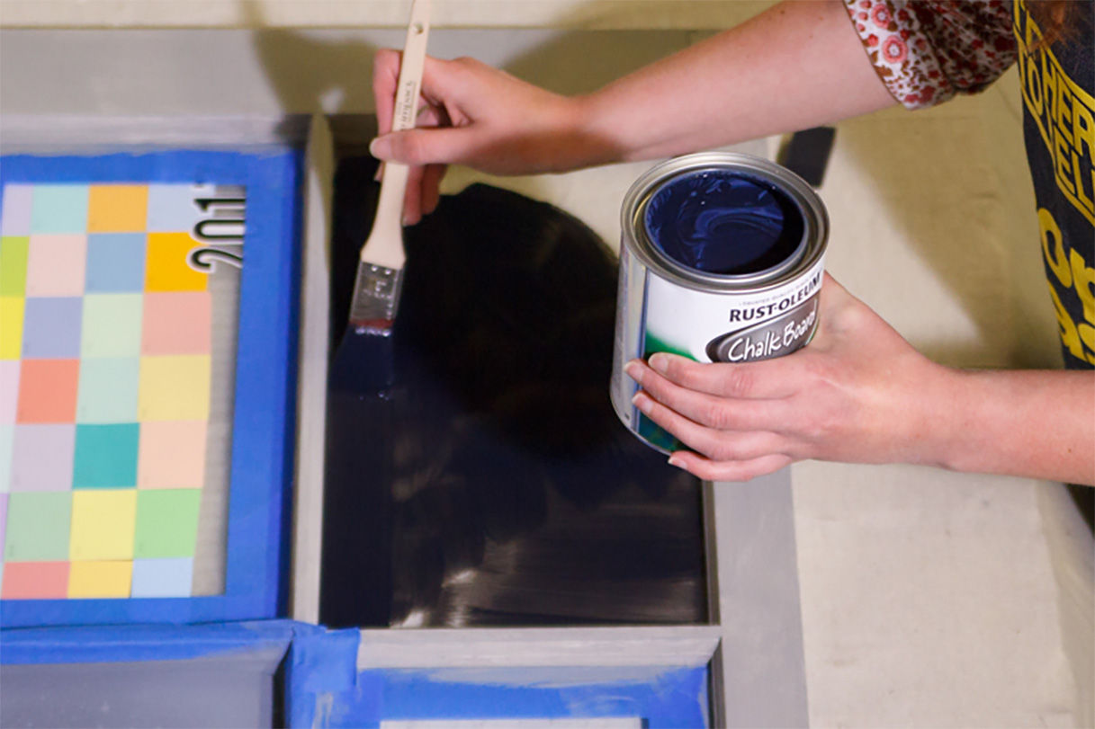 Person painting on chalk board paint after the primer has dried