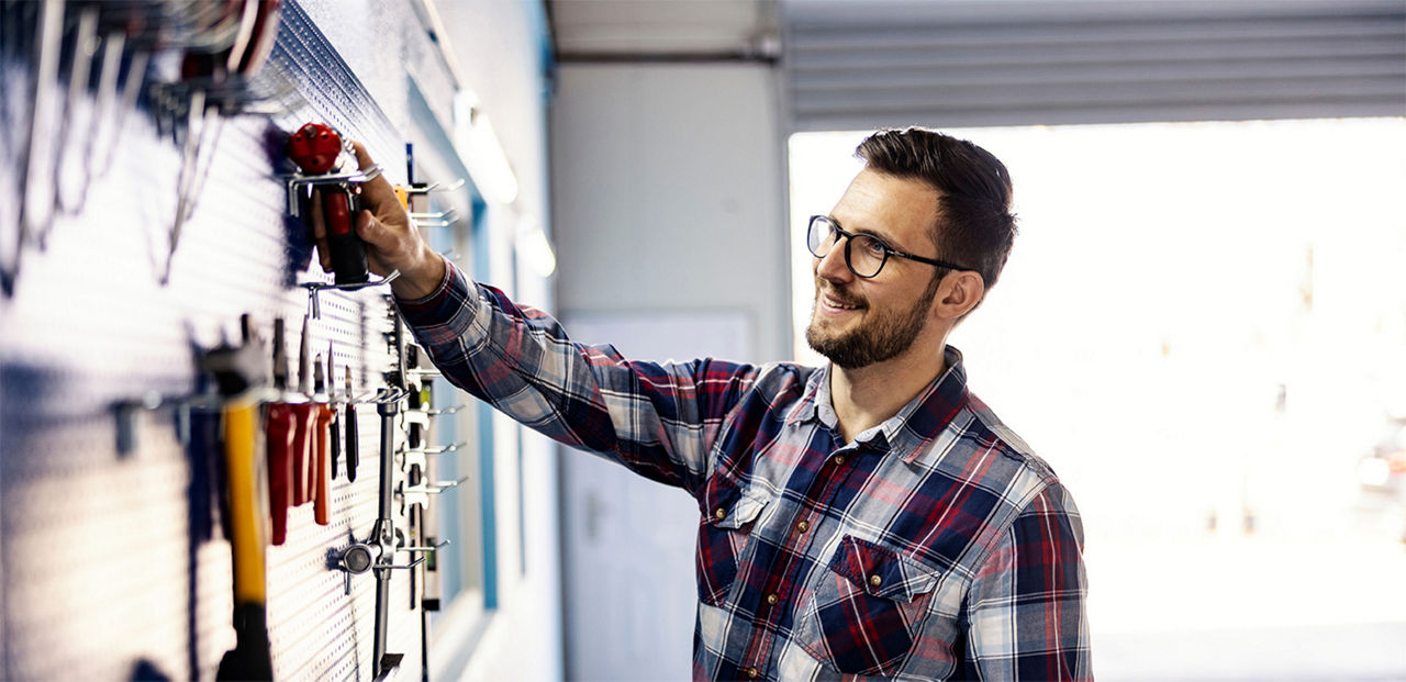 Man organizing his tool shelf on the wall