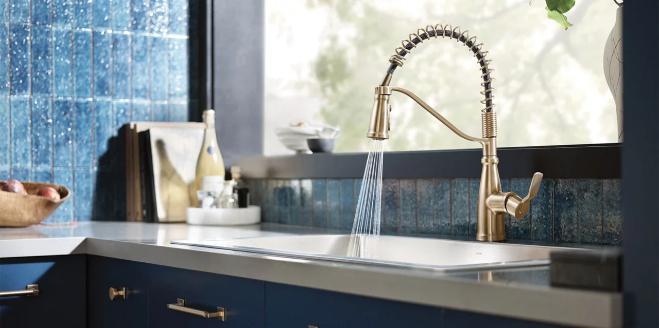 Gold Moen kitchen faucet with white countertops and blue tiled walls 
