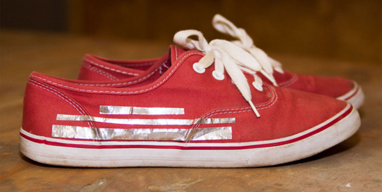 red sneakers with reflective duck tape on the side 