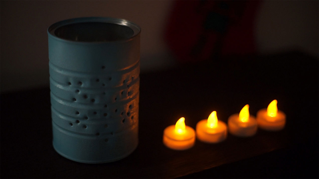 Finished blue holiday tin can next to tea lights 