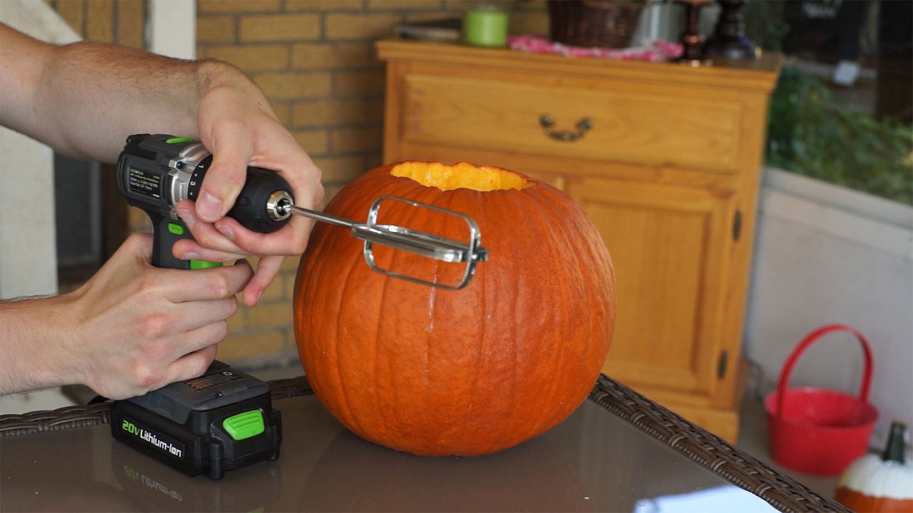 Person attaching a mixer beater to a drill near a pumpkin