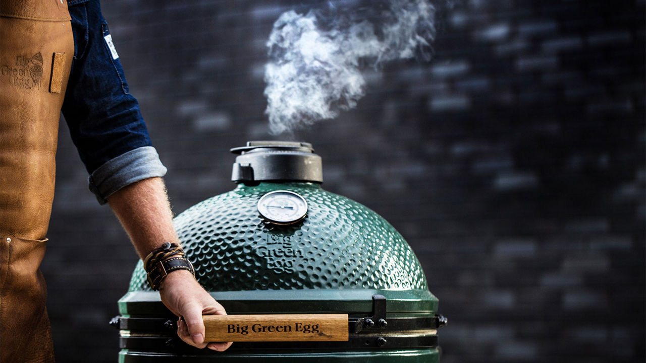 A man lifting the lid of a Big Green Egg