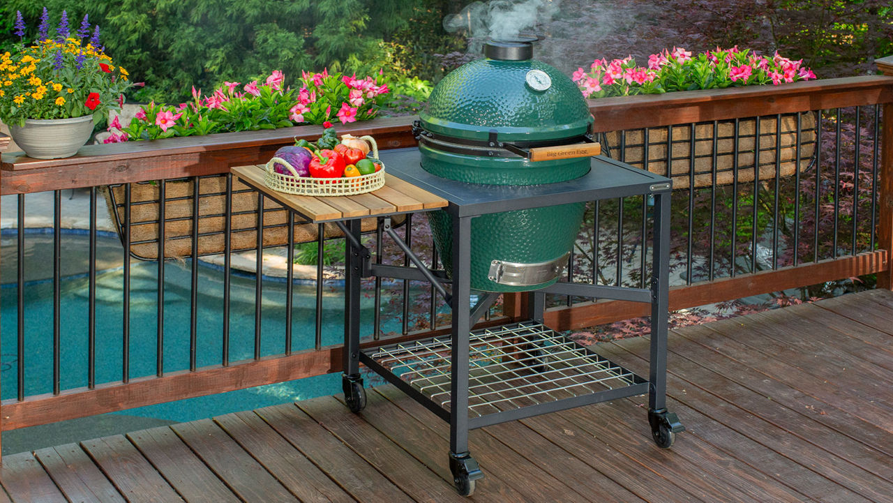 A Big Green Egg sitting in a nest on a deck