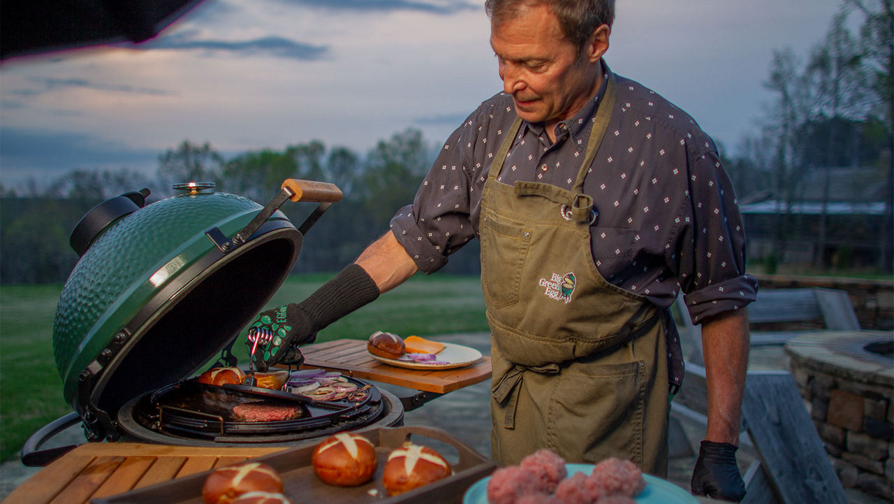 A man grilling burgers on a Big Green Egg