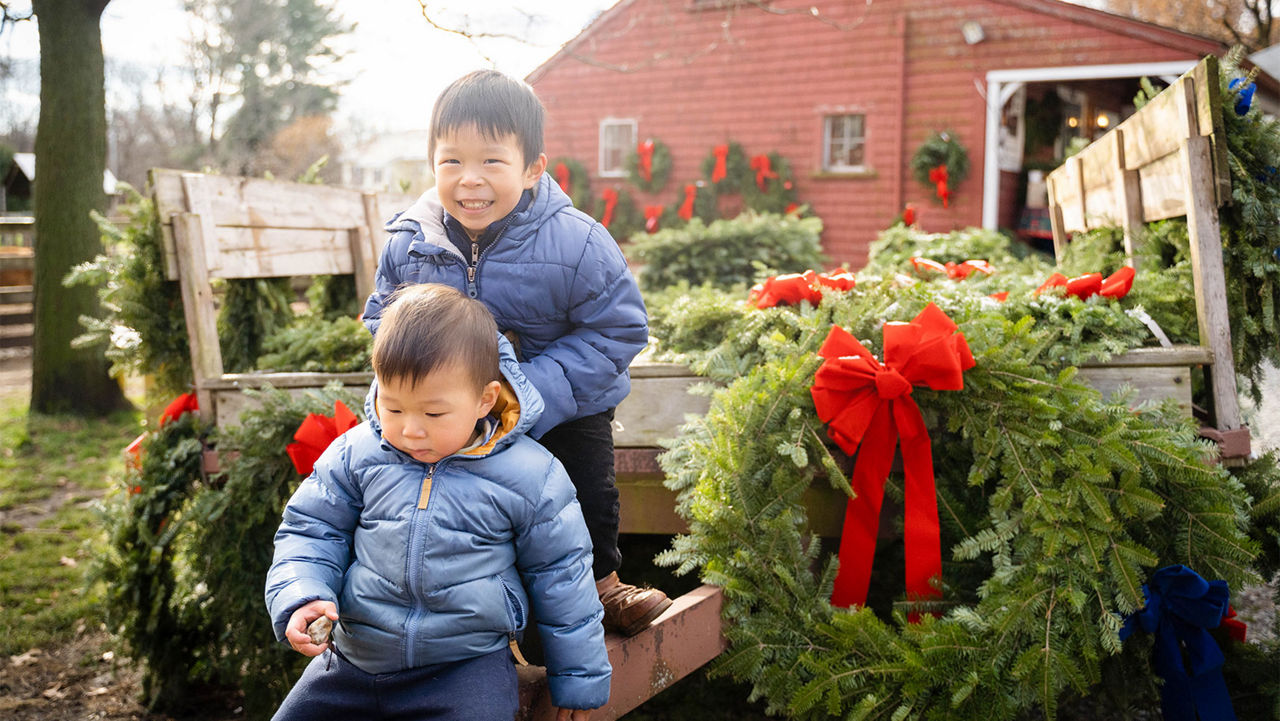 Two little boys sitting next to holiday wreaths