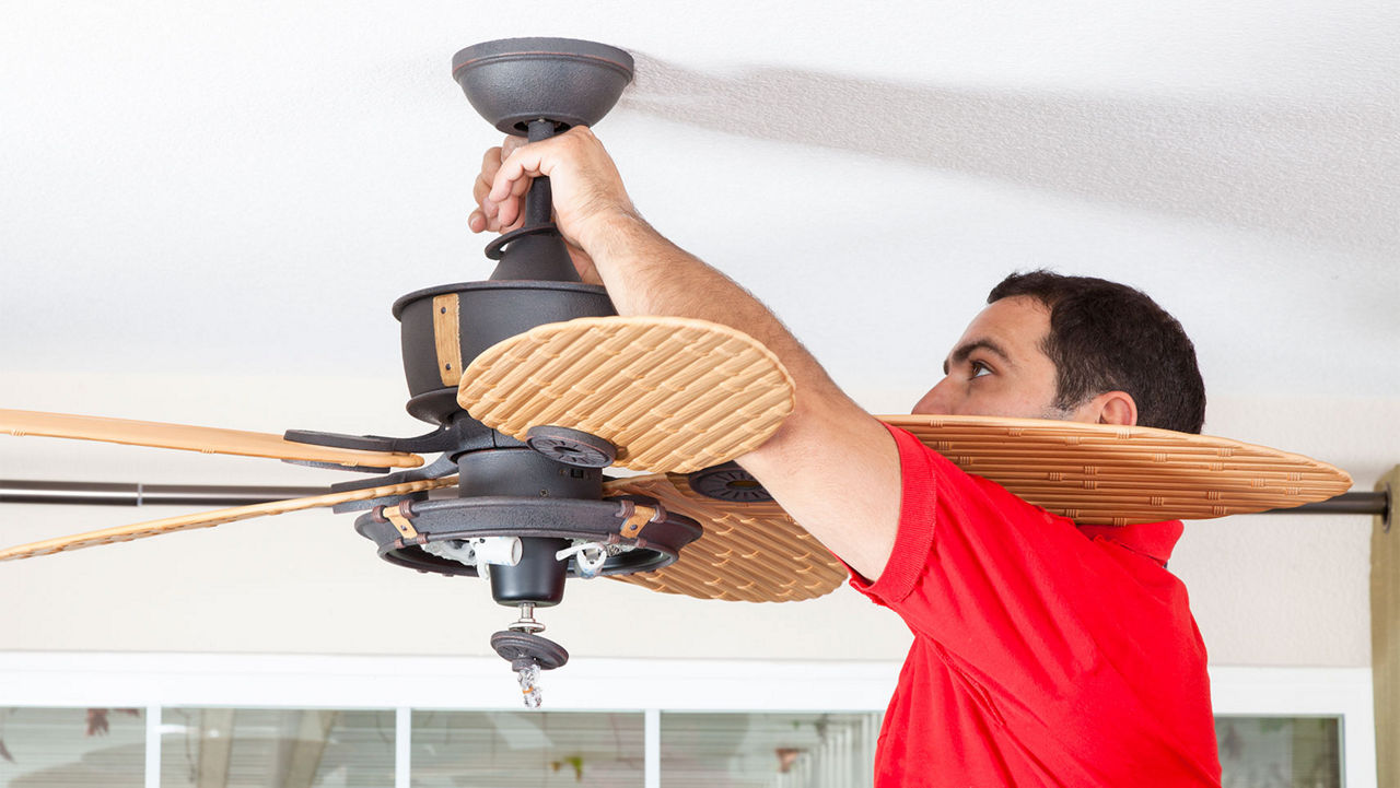 A man installing a ceiling fan