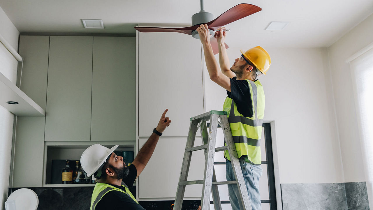Two workers installing a ceiling fan