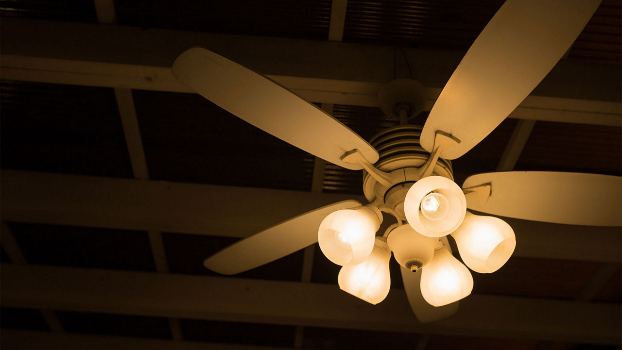 A ceiling fan with lights lighting up a dark room