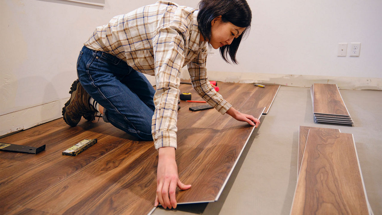 A woman installing laminate flooring