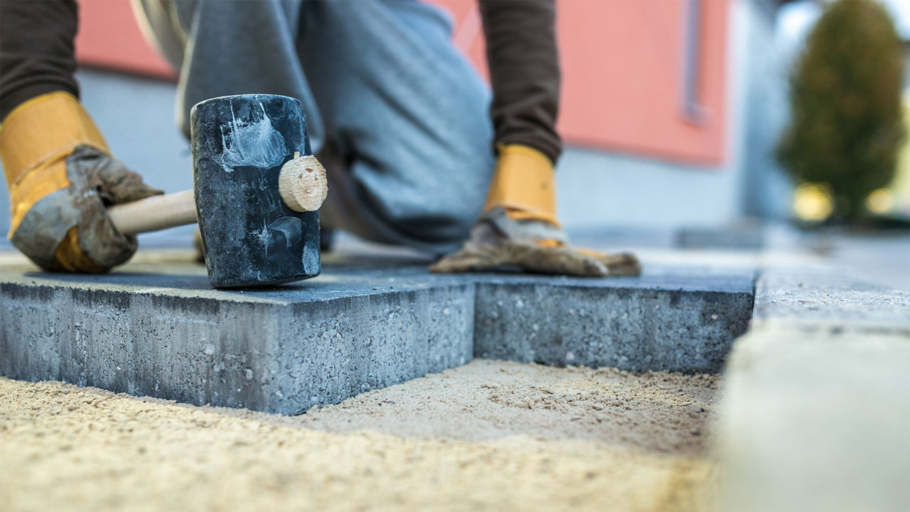 Man using a rubber mallet to level paver