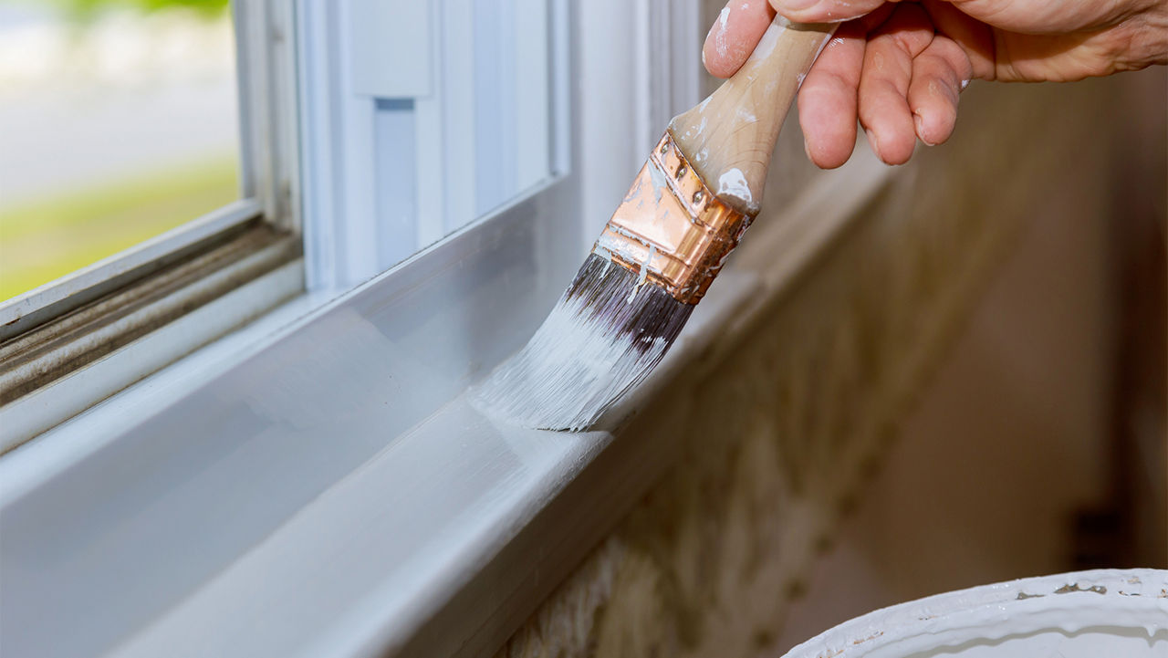 Touching up the paint around a window sill