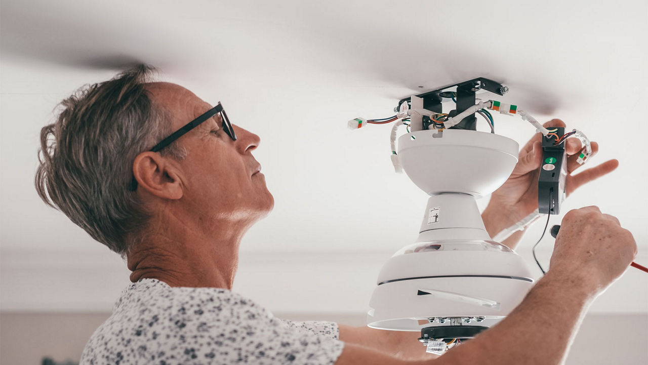 A man wiring a ceiling fan