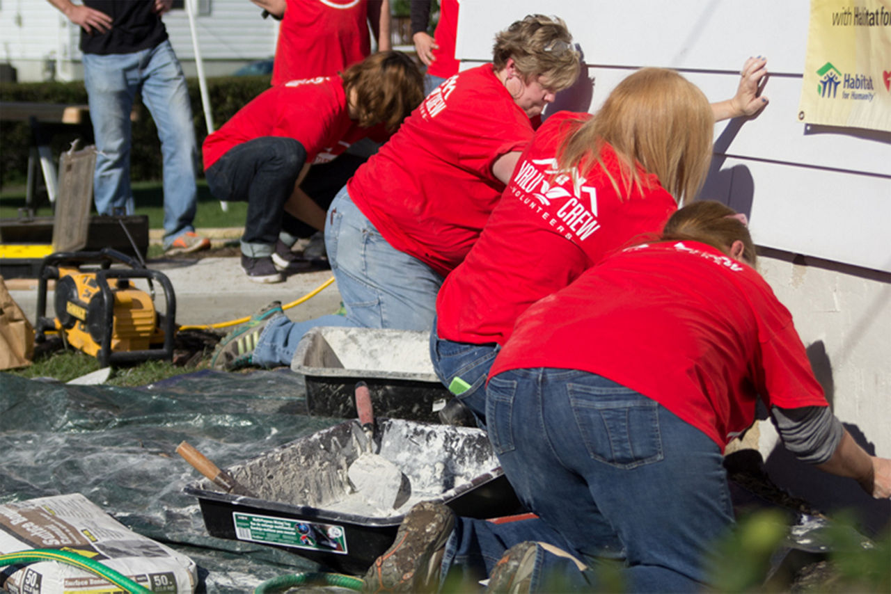 Women applying concrete to the foundation of the house