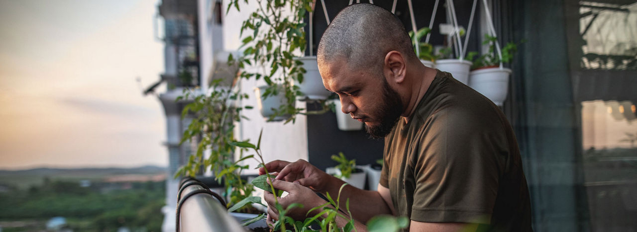 A man on a balcony tending to his plants 