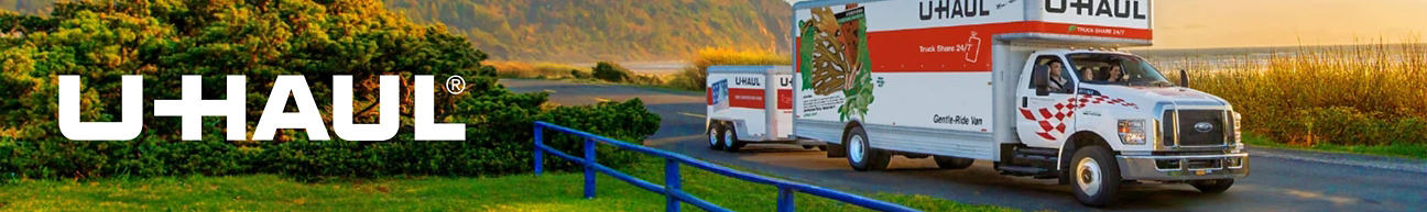 U-Haul truck and trailer driving down the road with a scenic landscape in the background