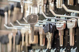 Blank silver keys hanging from hooks on a pegboard at a hardware store