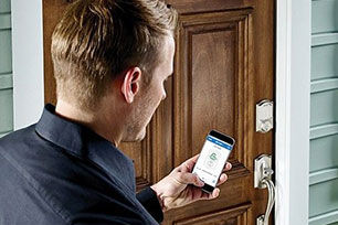 Man looking at his smart phone by the front door of his house