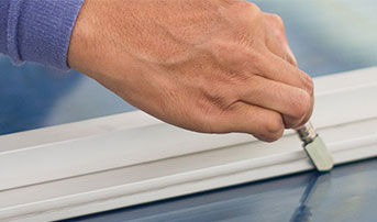 A close-up of a hand using a special tool and straight edge to cut glass