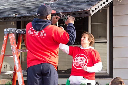 Two Valu Crew volunteers hanging up lights