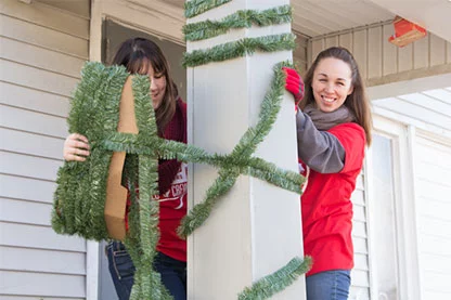 Two Valu Crew volunteers hanging garland