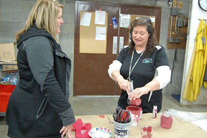 Two women working with red paint at a workshop