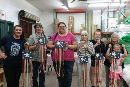seven women holding up a fourth of July paper craft at a workshop