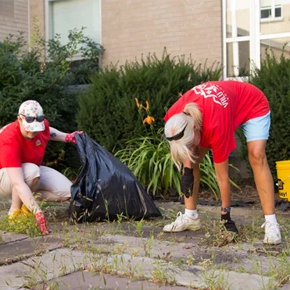 Two Valu Crew volunteers pulling weeds and bagging them