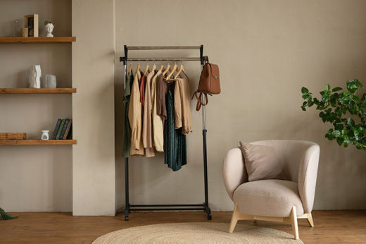 room with a chair and clothes on a rack