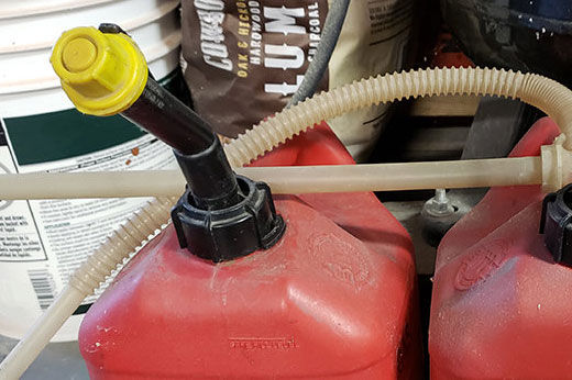 Two red gas cans with a siphon pump.