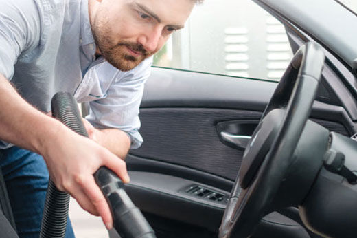 Man using a wet/dry vac to clean car