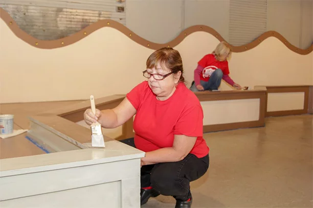 Valu member helping paint the Herschell Carrousel Factory Museum