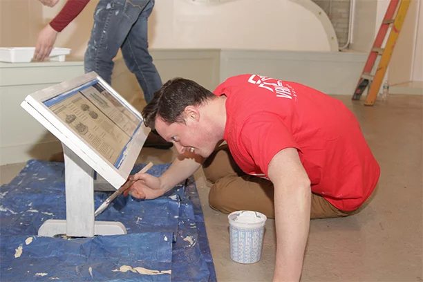 Valu member helping paint the Herschell Carrousel Factory Museum